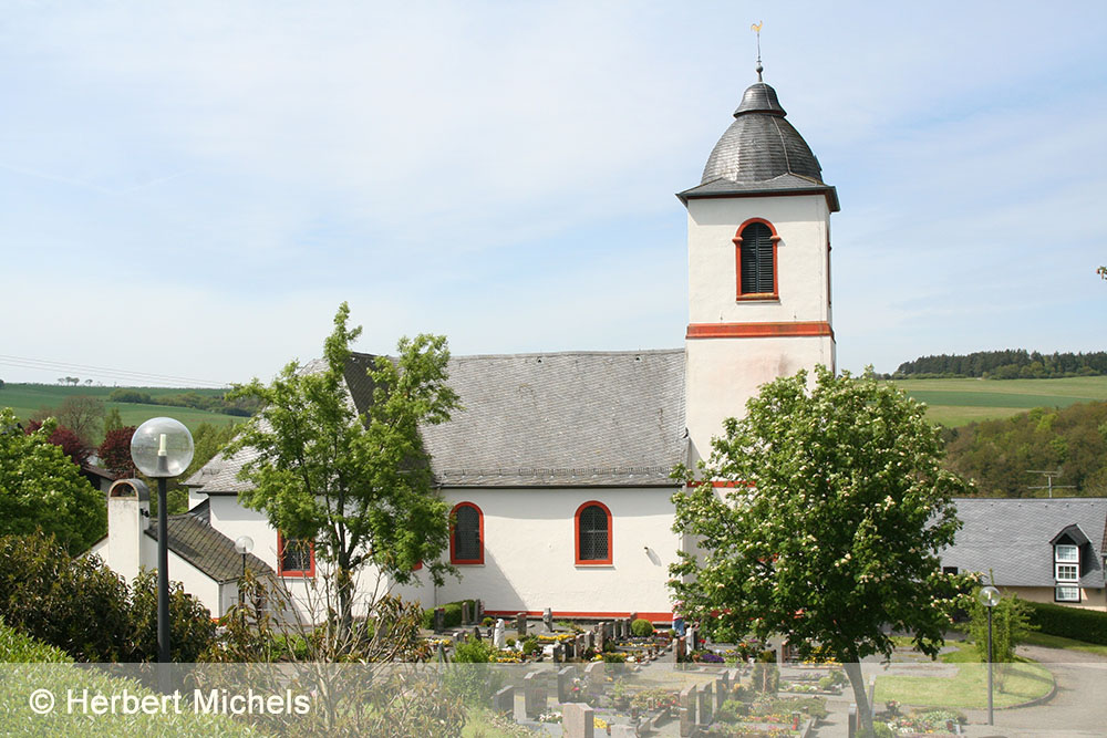 Außenansicht der Demerather Kirche mit Friedhof